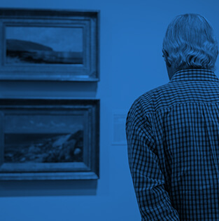 Man viewing framed landscape paintings in an art gallery