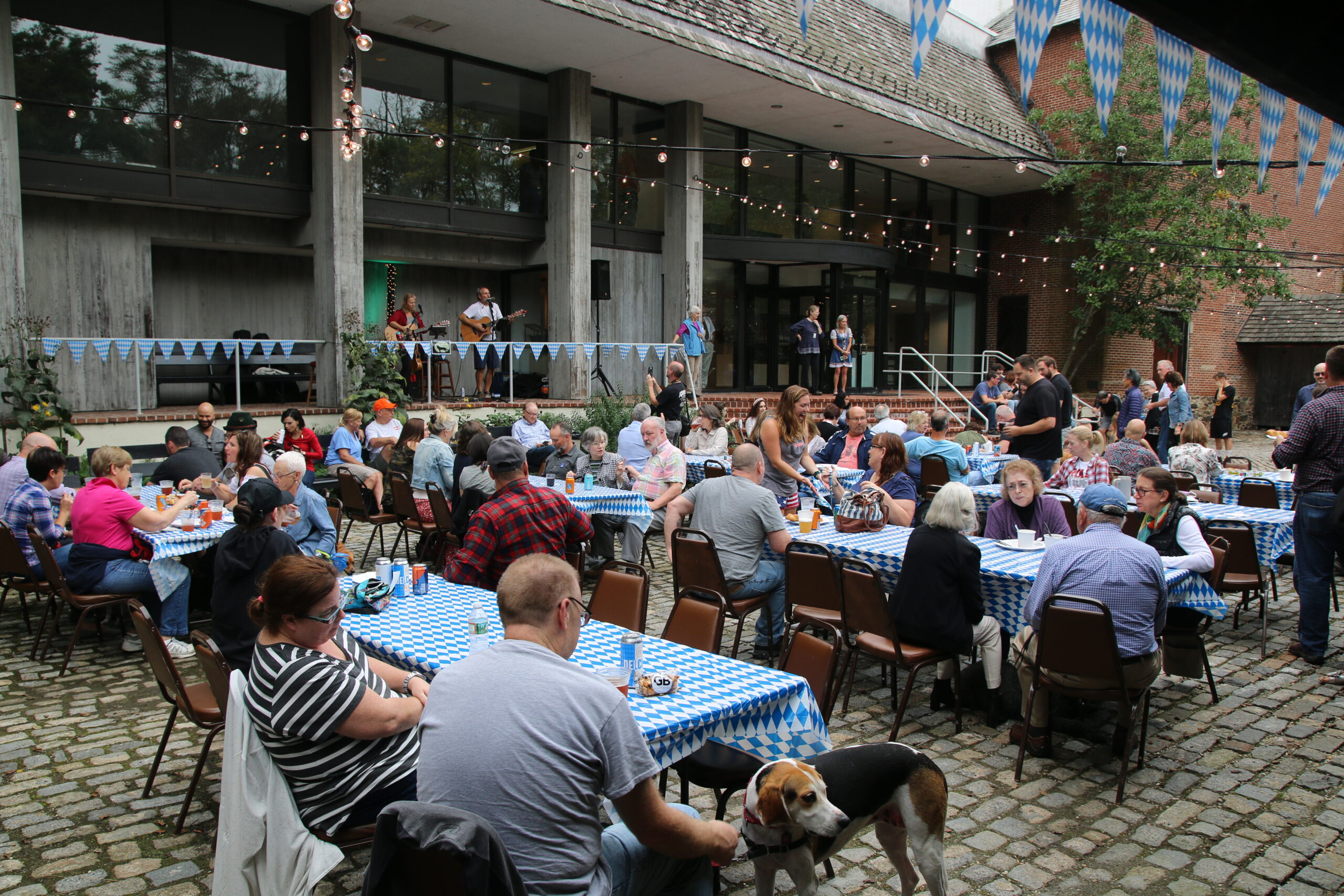 People gathered at outdoor tables with live music performance on stage.